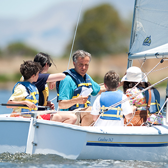 A group of kids in a boat wit an adult reading instructions A group of kids in a boat wit an adult reading instructions