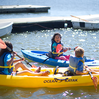 Kids playing around in their kayaks on a lake Kids playing around in their kayaks on a lake