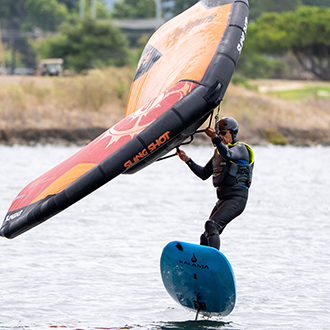 man windfoiling at shoreline lake A man jumping his wingfoil on shoreline lake.