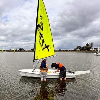 Two teens in the water with their boat. Two teens in the water with their boat.
