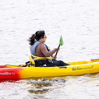 inan in a kayak on shoreline lake A womaan in a kayak on shoreline lake
