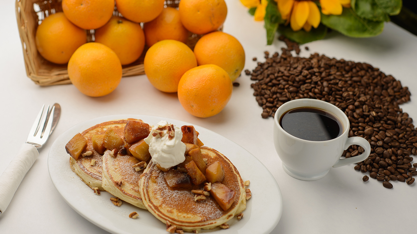 A breakfast spread with pancakes, coffee and oranges. A breakfast spread with pancakes, coffee and oranges.