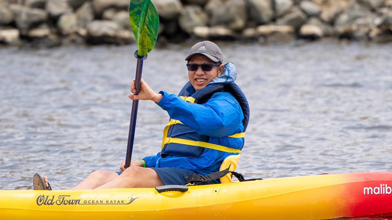 A person in a kayak on shoreline lake. A person in a kayak on shoreline lake.