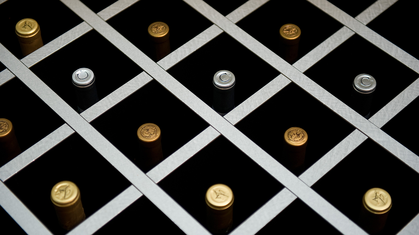 Tops of wine bottles in a display case.